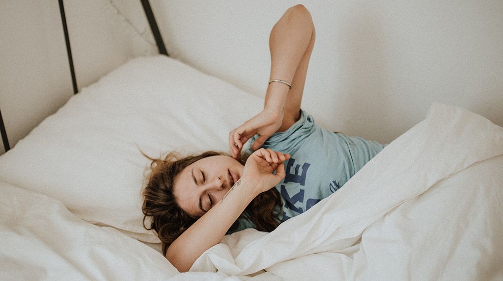 Is sleeping on your side good for you: a woman lays on her side in bed