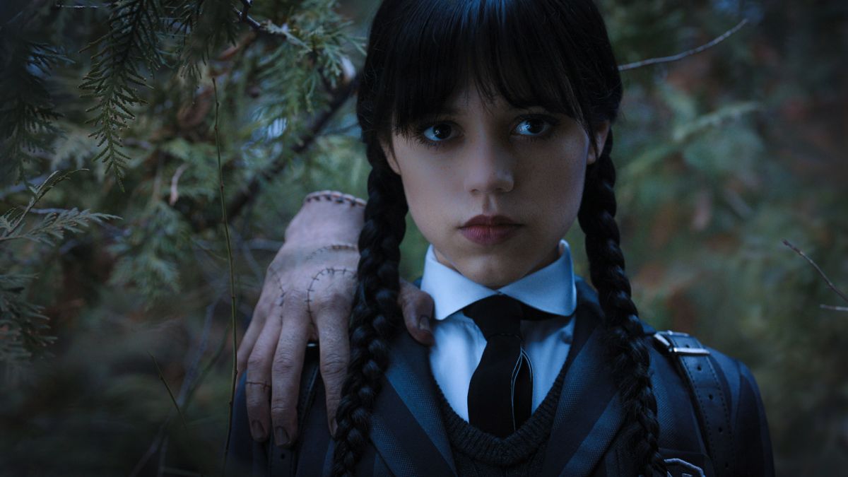 A close up of Wednesday Addams, with Thing standing on her shoulder, in Wednesday