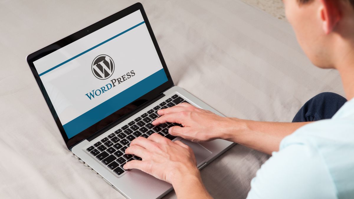 Wordpress brand logo on computer screen. Man typing on the keyboard.