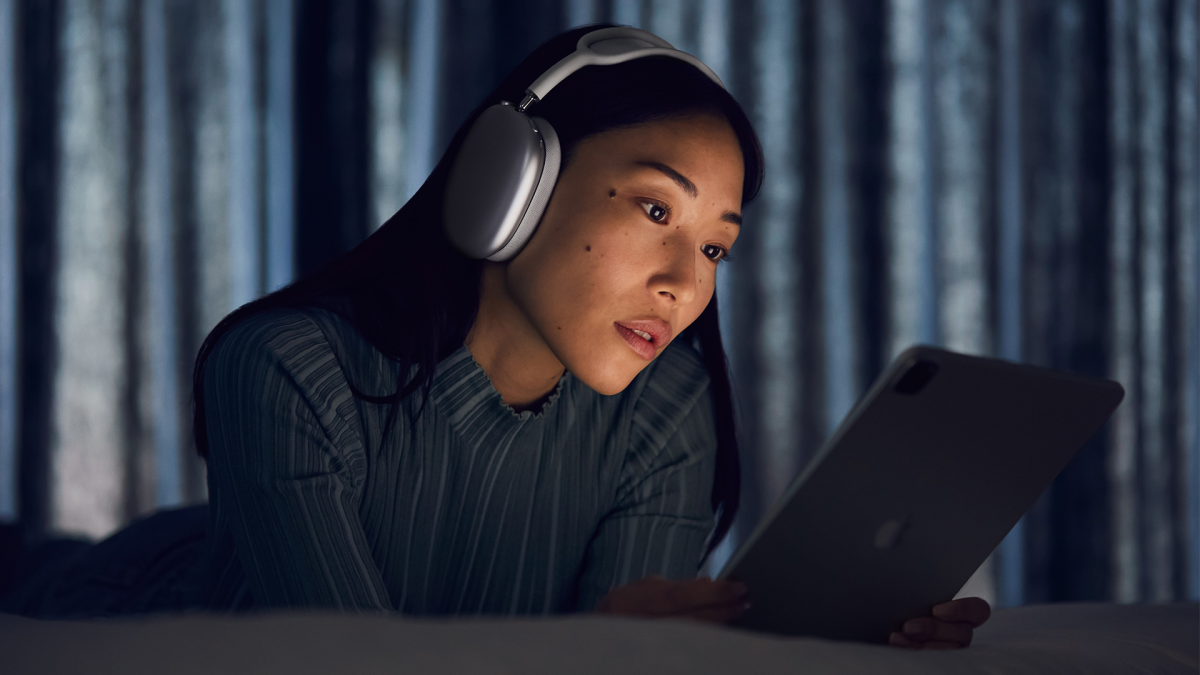 A person wearing the Apple AirPods Max while using an iPad