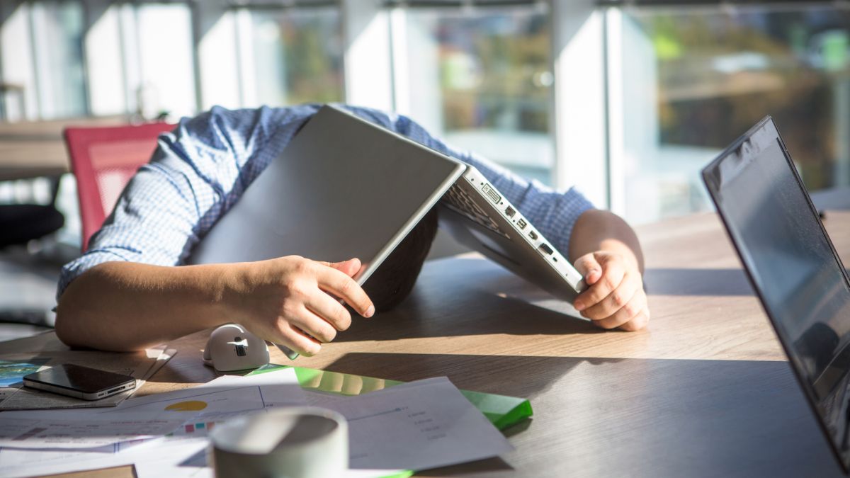 man sleeping underneath his laptop