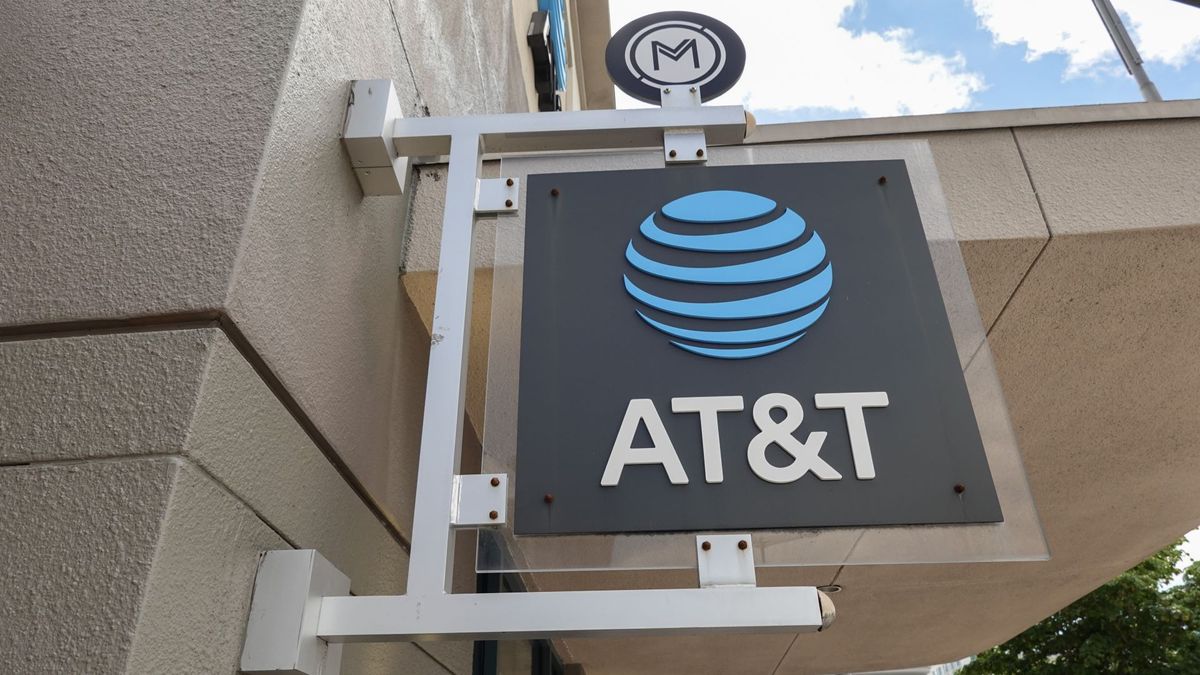 A black AT&T sign with its logo in bright blue hanging outside a brick store